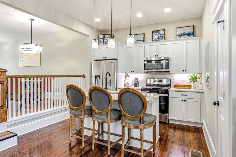 Open kitchen with stainless appliances, a gas range, island seating, and a fully stocked coffee bar.