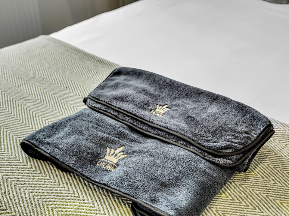 Plush branded towels and a neatly styled bed for a hotel-like stay
