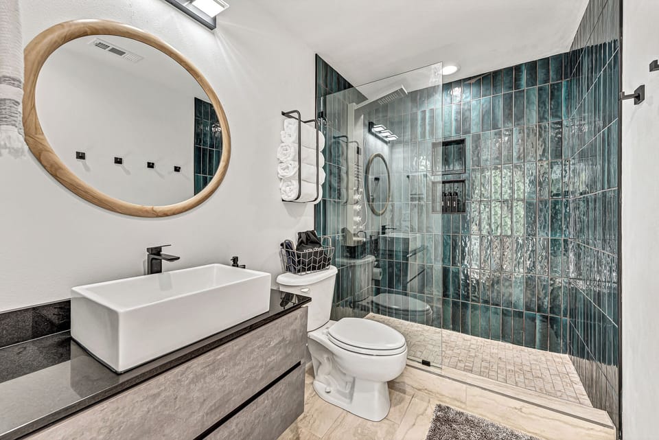 Modern bathroom with a stunning teal-tiled shower area.