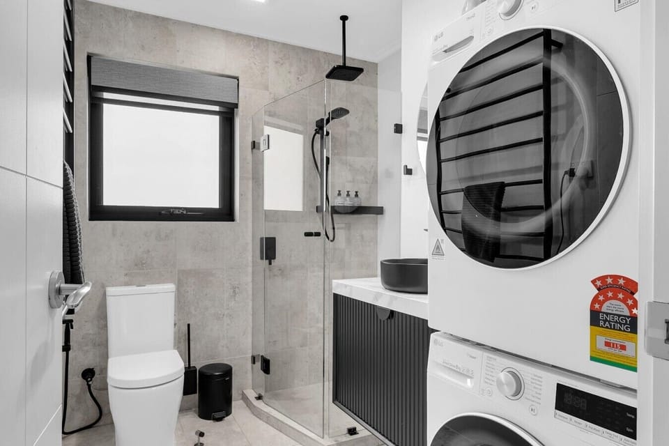 Modern bathroom with glass shower and black fittings.