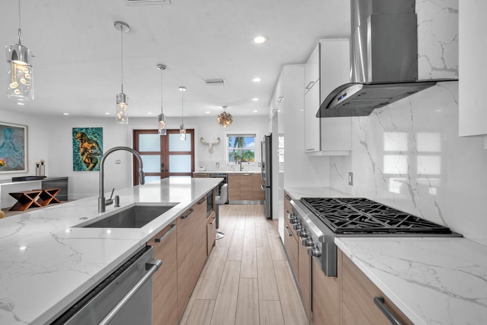 Polished kitchen with a waterfall island, high-end appliances, and a bright view toward the outdoor dining area.