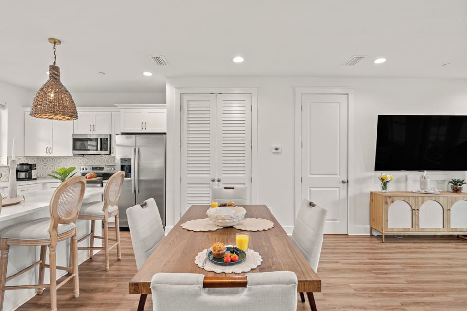 Spacious dining area and coastal kitchen with island seating, woven pendants, and easy backyard access.