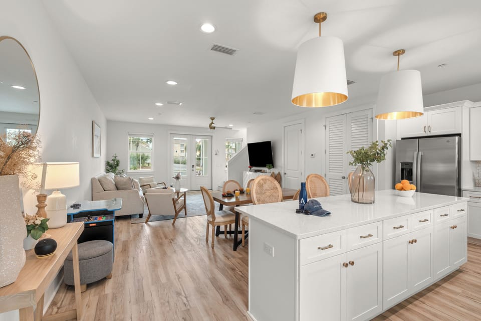 Bright coastal kitchen with island seating, full appliances, and easy access to the pool.