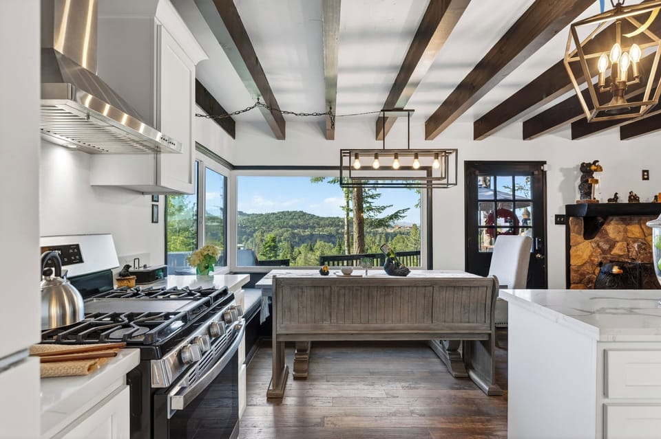 Mountain-view kitchen and dining space with rustic beams, warm lighting, and easy deck access.