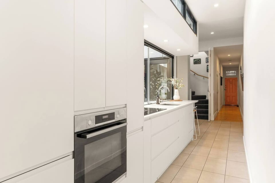 The spacious kitchen offers integrated appliances, abundant cabinetry and a long preparation bench.