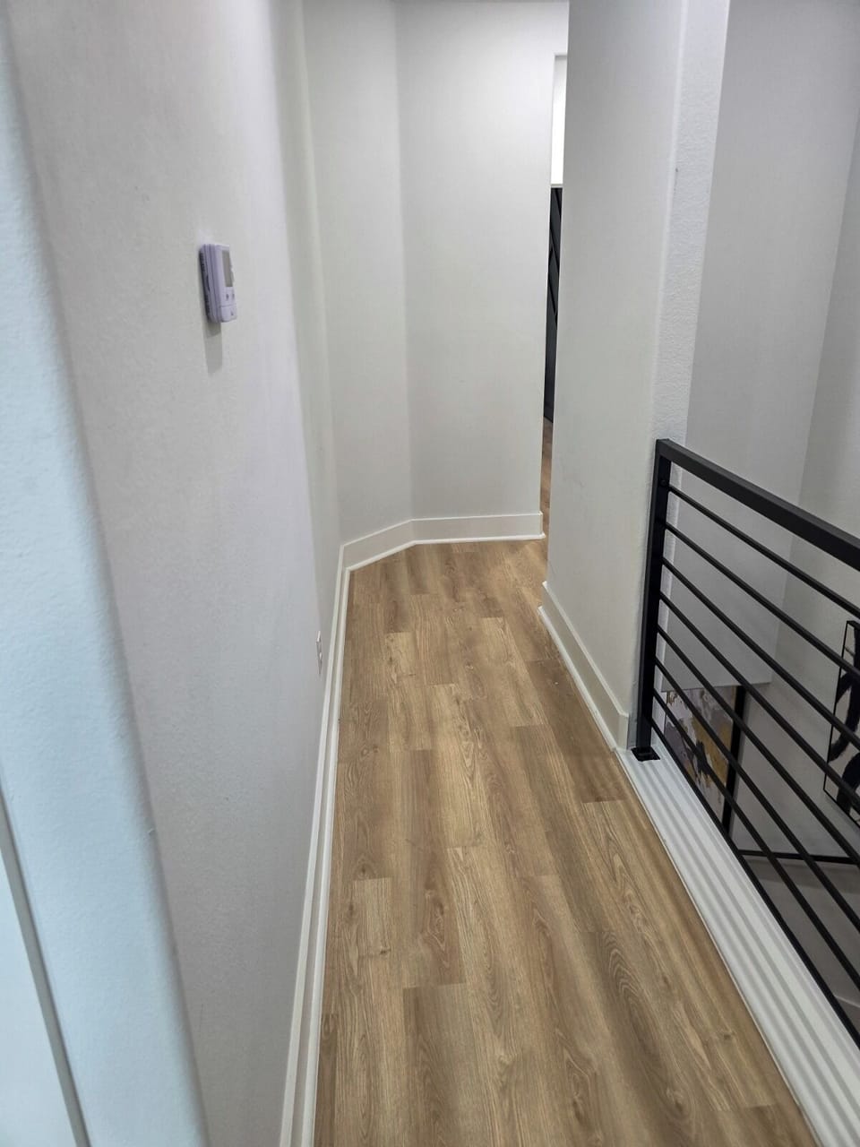 Bright modern hallway with stylish wood floors and sleek stair railing