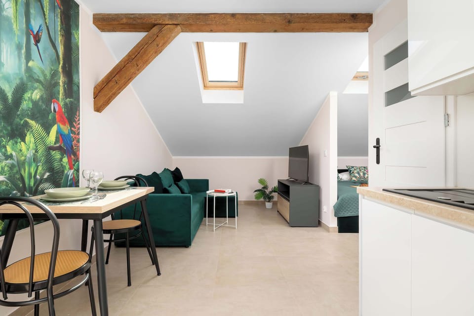 Open-plan studio combining the dining area, kitchenette and lounge with elegant tropical wall art.