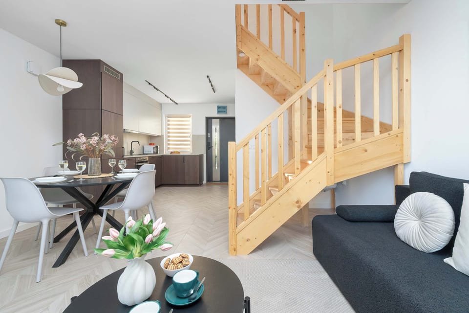 A comfortable lounge area with a sofa, coffee table, and a wooden staircase as the focal point.
