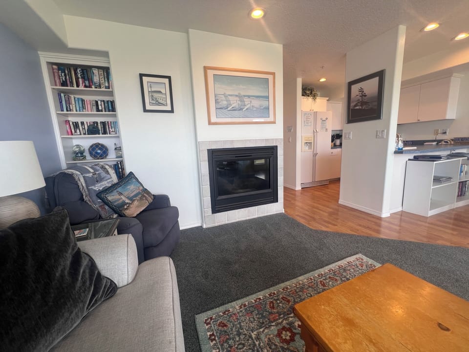 Cozy living space with fireplace, full kitchen, and thoughtful touches like built-in bookshelves and artwork—your perfect retreat for relaxing evenings in.