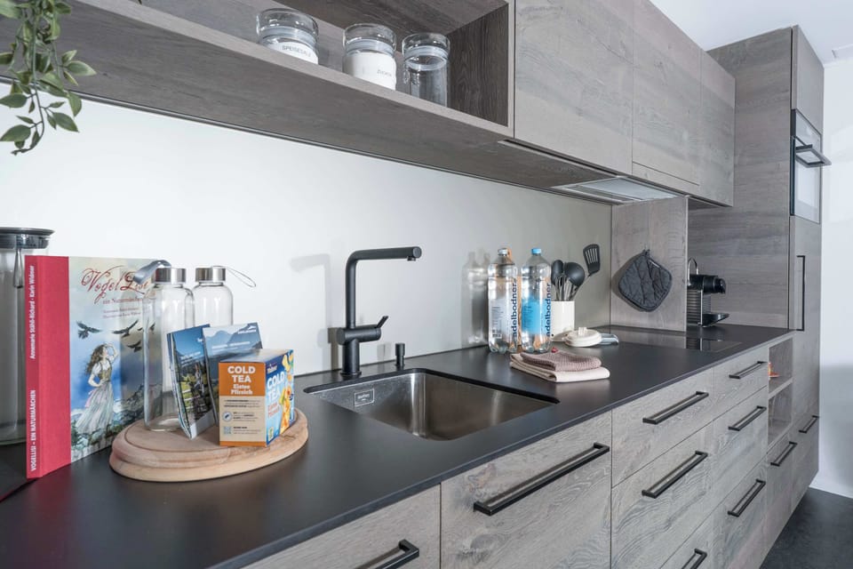Modern kitchen with coffee machine, oven, dishwasher, and cooking essentials.
