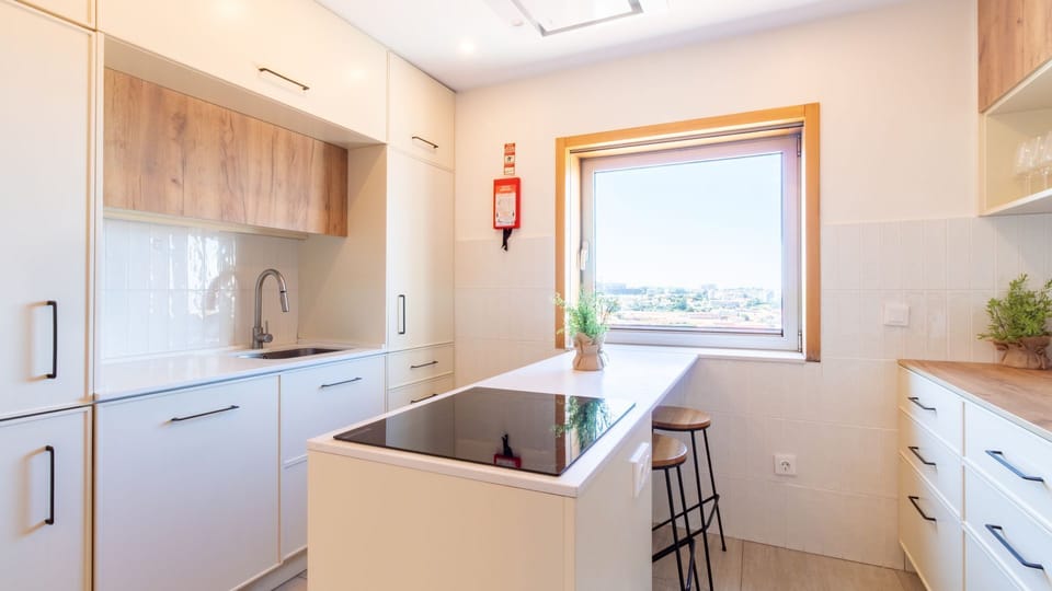 Prepare delicious meals in this bright, fully equipped kitchen featuring a modern induction cooktop and a cozy breakfast bar with stunning city views. Enjoy morning coffee or a quick bite while soaking in the panoramic scenery. #ModernKitchen #CityView #B