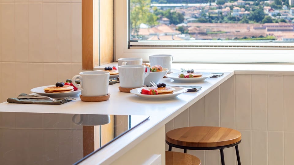 Start your day right with a beautiful breakfast spread, perfectly laid out on the kitchen's breakfast bar, offering captivating views of the city. This spot is ideal for savoring leisurely mornings and planning your adventures. #BreakfastNook #CityViews #