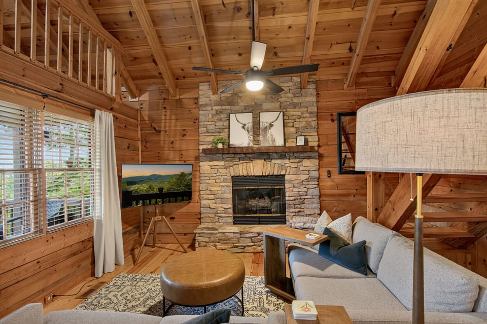 Cozy cabin living room with stone fireplace and soaring wood ceilings