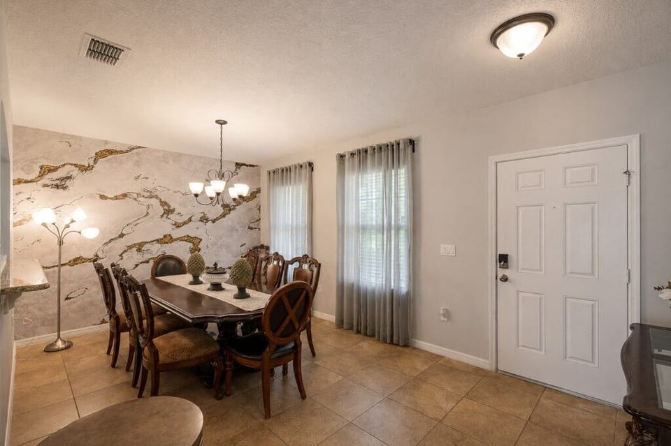 Elegant dining room with marble accent wall and seating for eight.