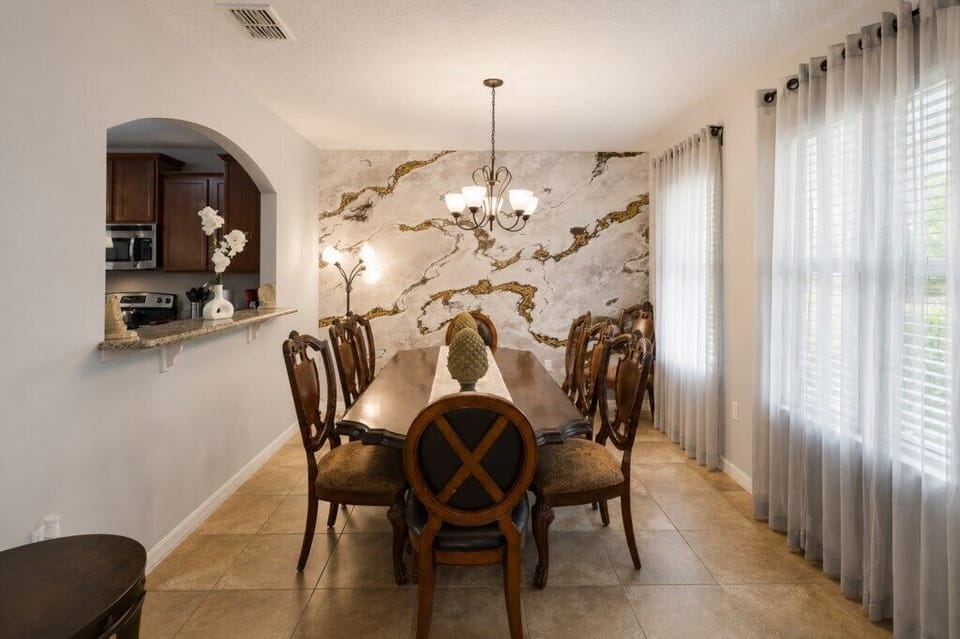 Elegant dining room with marble accent wall and seating for eight.