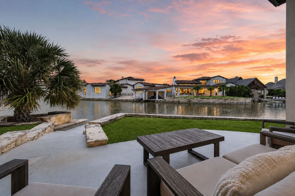 Patio seating area overlooking a canal and neighboring homes at sunset.