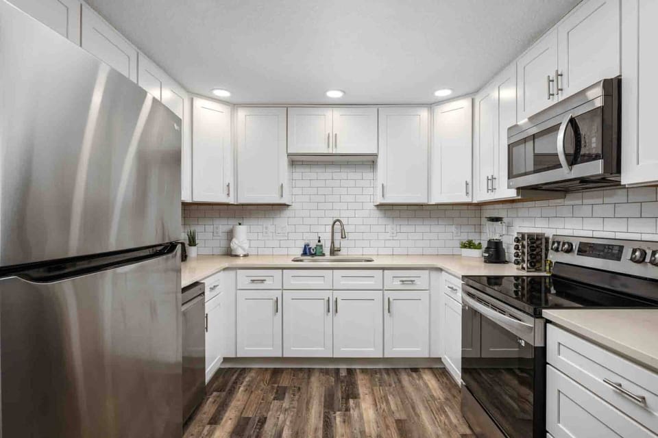 Bright, modern kitchen with stainless steel appliances, white shaker cabinets, subway tile backsplash, and ample counter space for meal preparation.