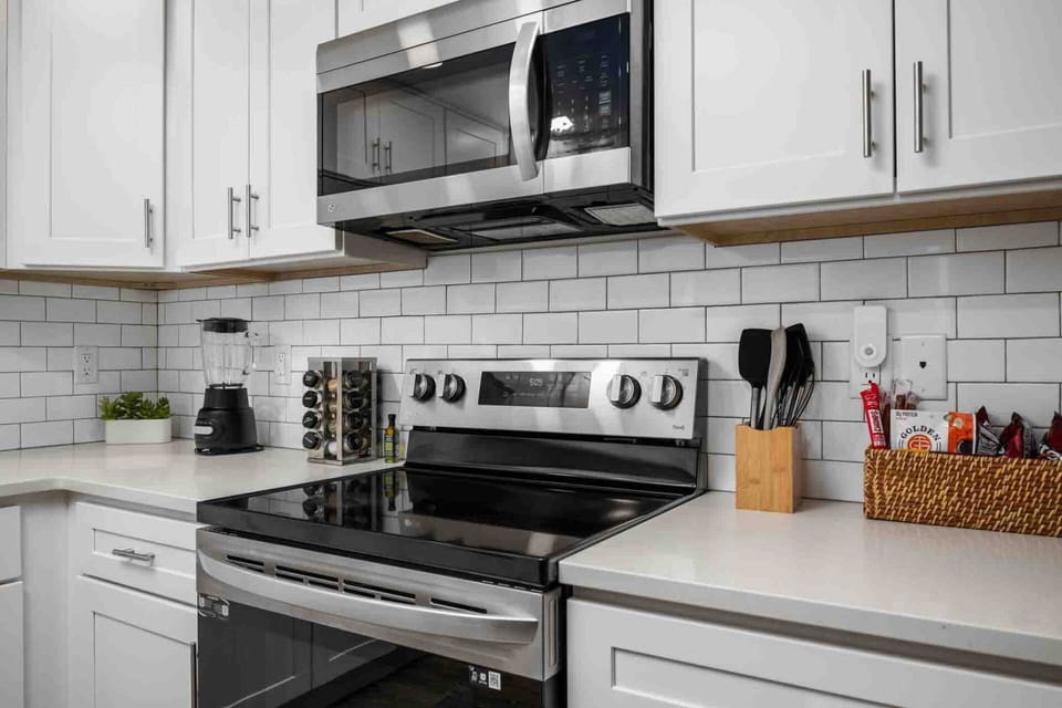 Well-equipped kitchen featuring stainless steel appliances, a microwave, coffee maker, blender, cooking essentials, and plenty of counter space.