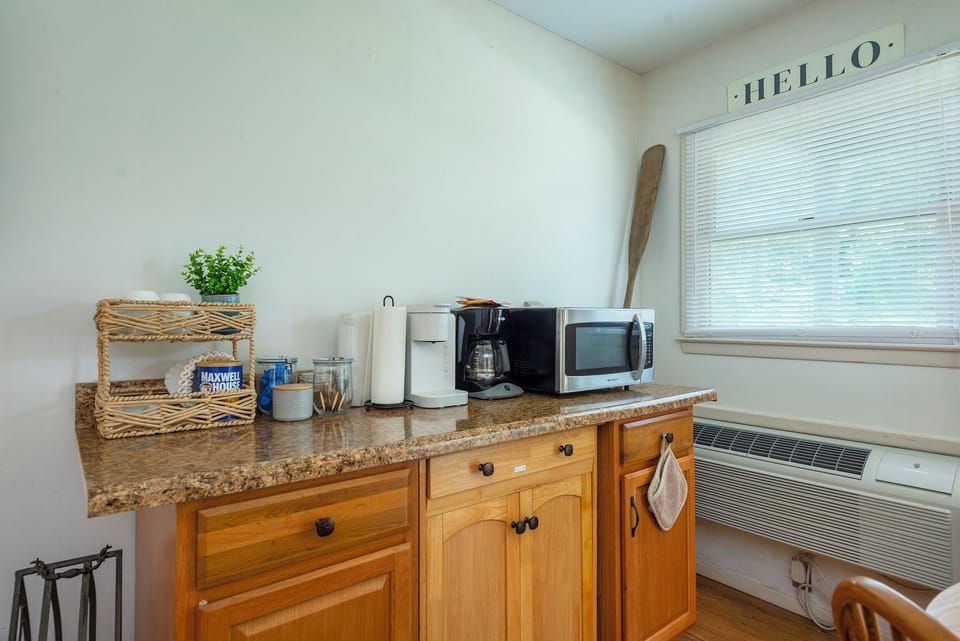 The opposite side of the kitchen includes a microwave and two coffee makers.