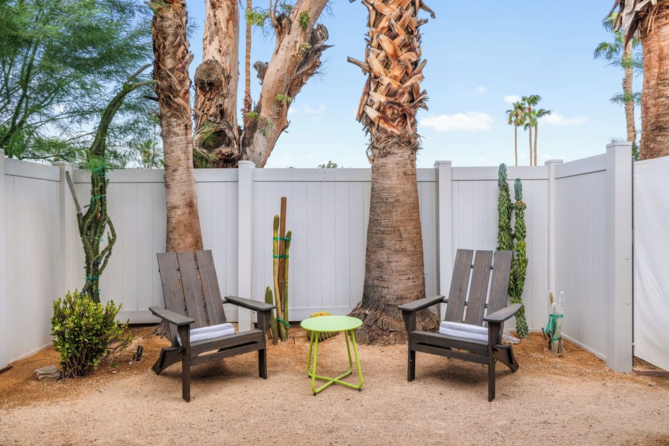 Private outdoor sitting area with Adirondack chairs, desert landscaping, and direct bedroom access.