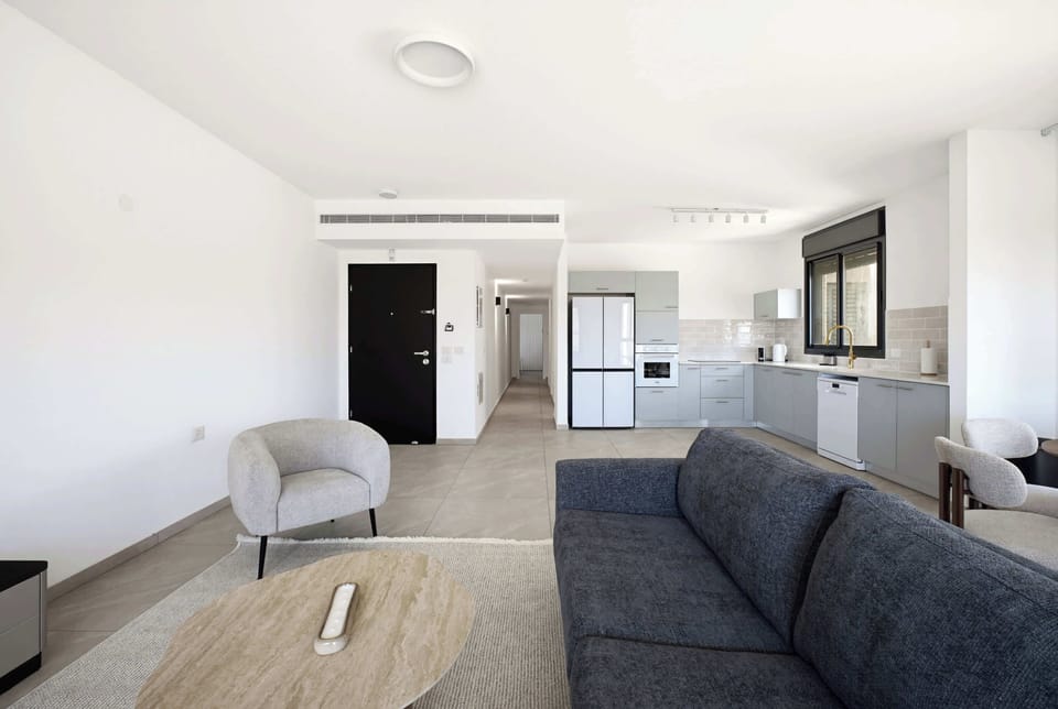 Contemporary studio layout showcases efficient furniture arrangement, warm wood finishes, soft furnishings, and sunlit alcove for relaxation.
