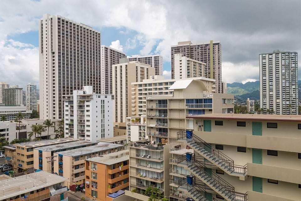 The property is located in a vibrant urban neighborhood with high-rise buildings and mountain views visible in the surrounding area.