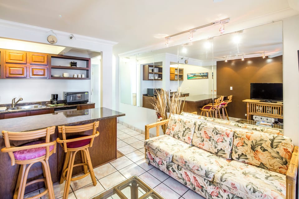 Step into your bright open-concept space where kitchen, dining, and living blend seamlessly. Cook, unwind on comfy floral seating, watch TV, or gather around the island—it's all here for you.