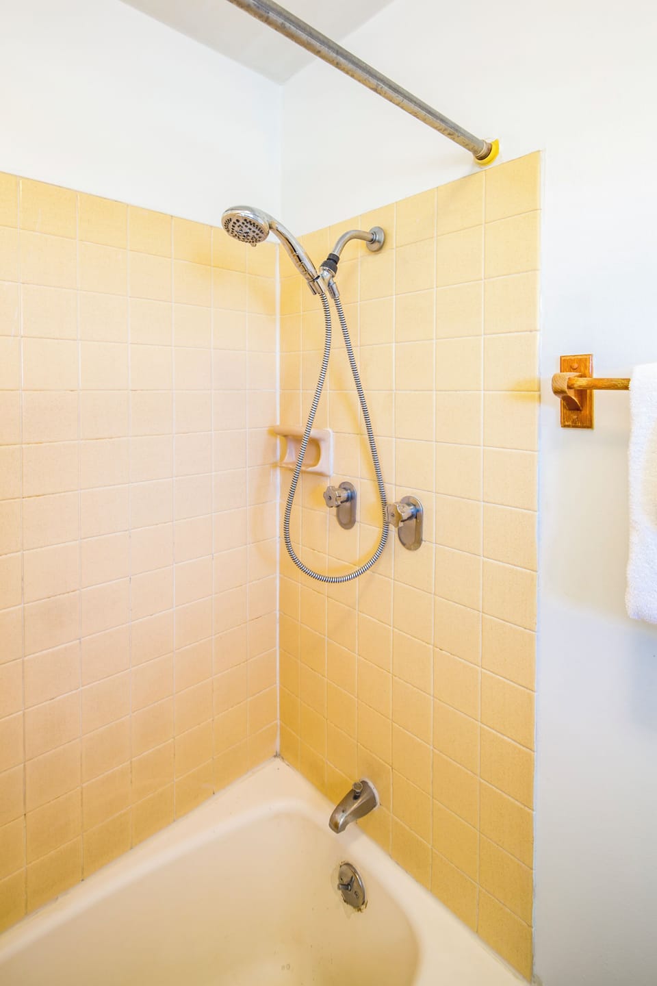 Bright, tiled tub-and-shower combo ready for your refreshing morning routine or relaxing evening soak. Soft towels hang nearby for your comfort.