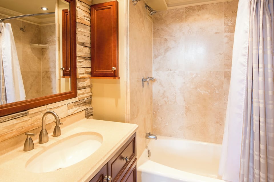 Your private bathroom features elegant travertine tile, a deep soaking tub, and warm wood accents—perfect for unwinding after a day of adventure.