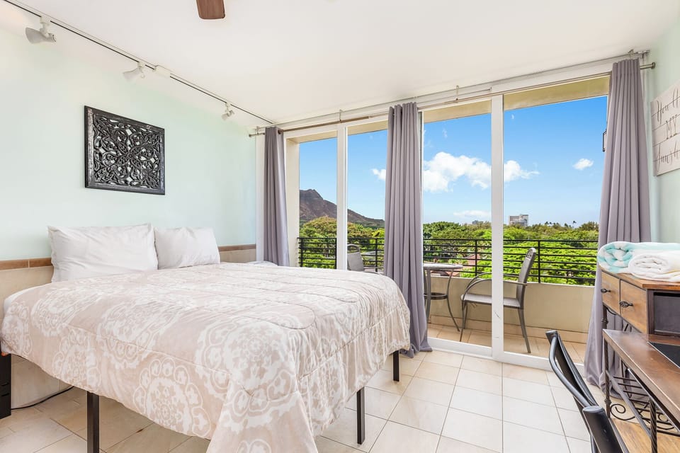 Bright bedroom with a plush bed and glass doors opening to your private balcony. Enjoy serene mountain and greenery views from your tranquil retreat.