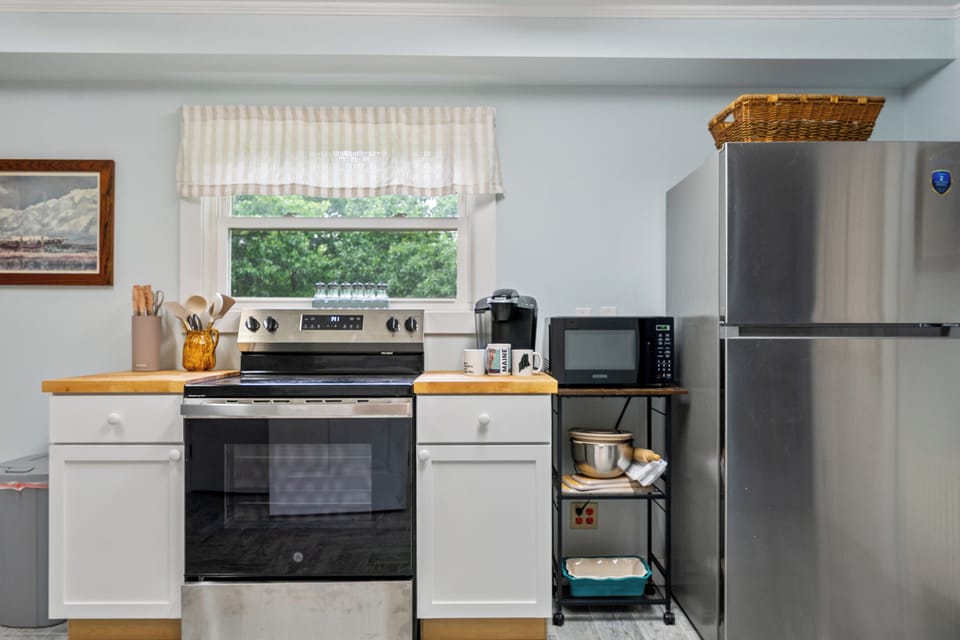 This straight-on view details our fully equipped kitchen's stainless steel range and refrigerator. Complete with butcher block countertops and an accessible microwave station, this functional layout maximizes meal prep efficiency for your Maine vacation.