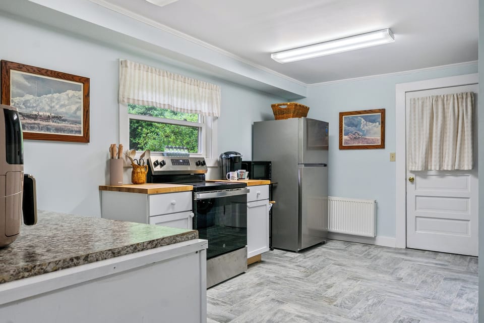 Enjoy plenty of room to cook and brew your morning coffee. This kitchen view highlights the stainless steel appliances, premium GE range, and butcher block surfaces, creating a functional, bright space to prep meals before going on an adventure.