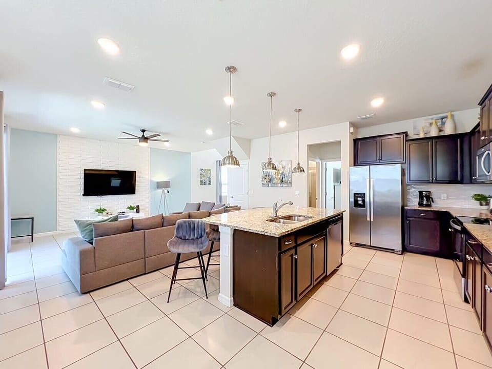 Fully equipped kitchen with stainless steel appliances, granite countertops, and a spacious island overlooking the living area.
