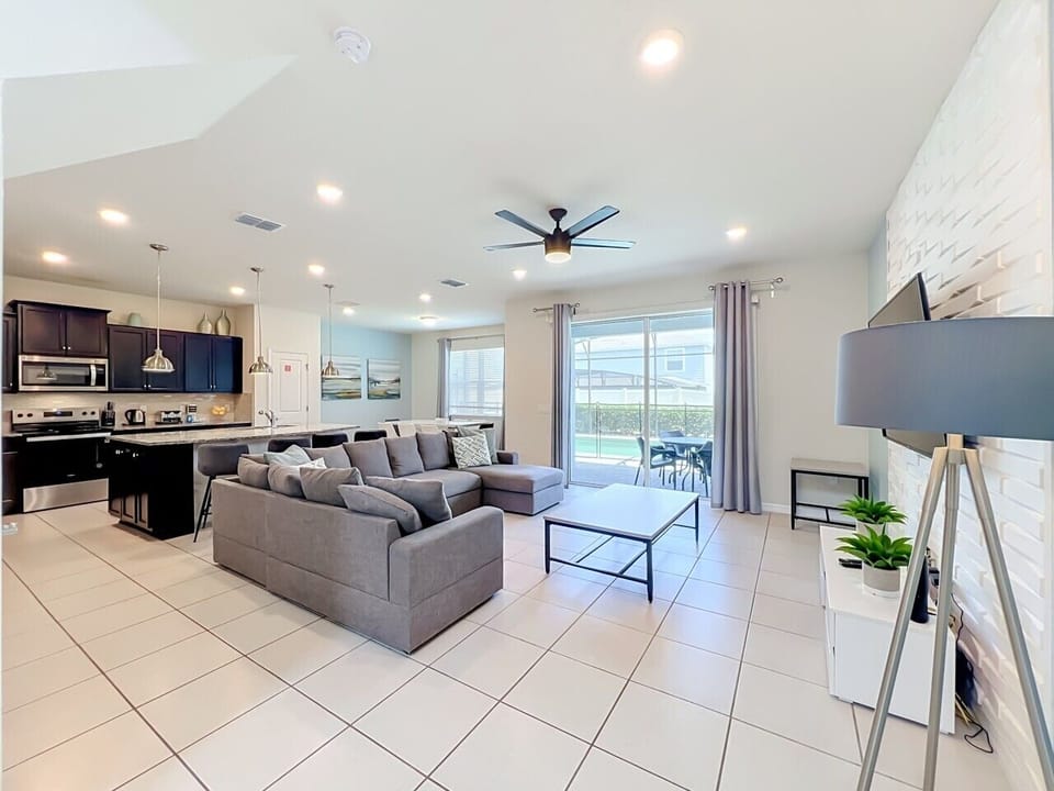 Relax in the open-concept living room featuring comfortable seating, a large smart TV, and direct access to the private patio.