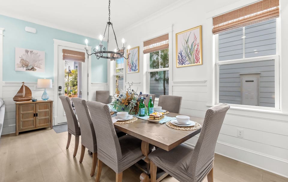 Gather around this inviting dining table where coastal-inspired art and bright natural light create the perfect setting for your morning coffee or evening meals together.