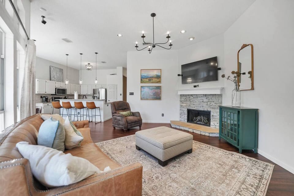 Inviting living space featuring a chic leather sofa, and cozy armchair. Enjoy movie nights on the smart TV or unwind with views of the open kitchen and dining area. Fireplace not operable due to regulations.