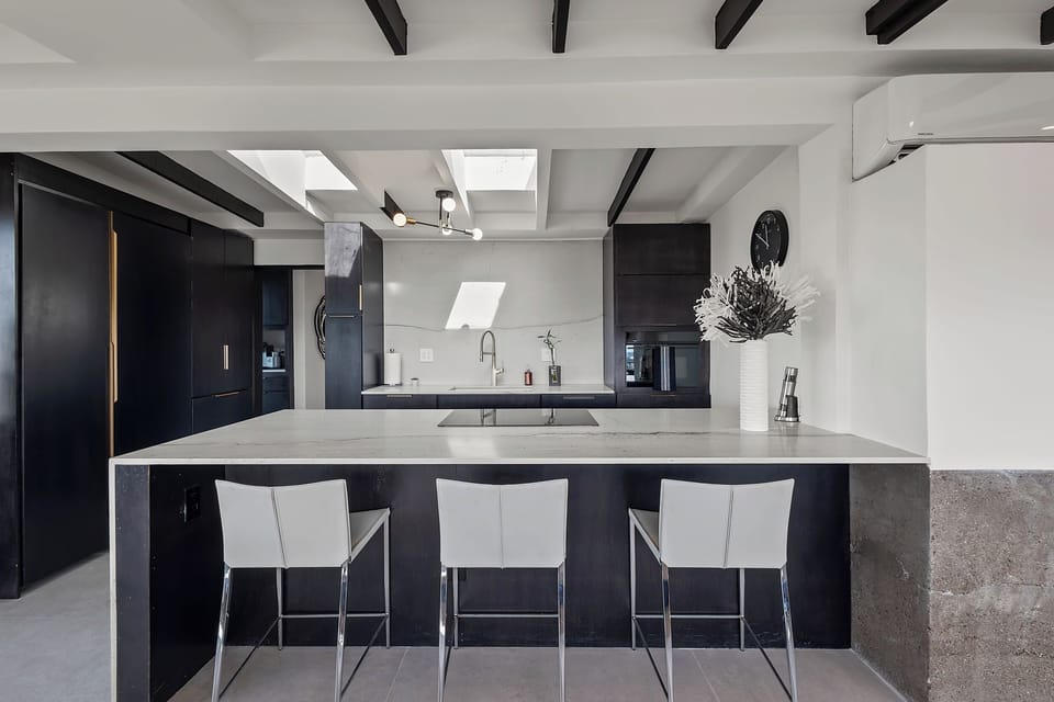 Modern chef’s kitchen with skylights, waterfall island and bar seating