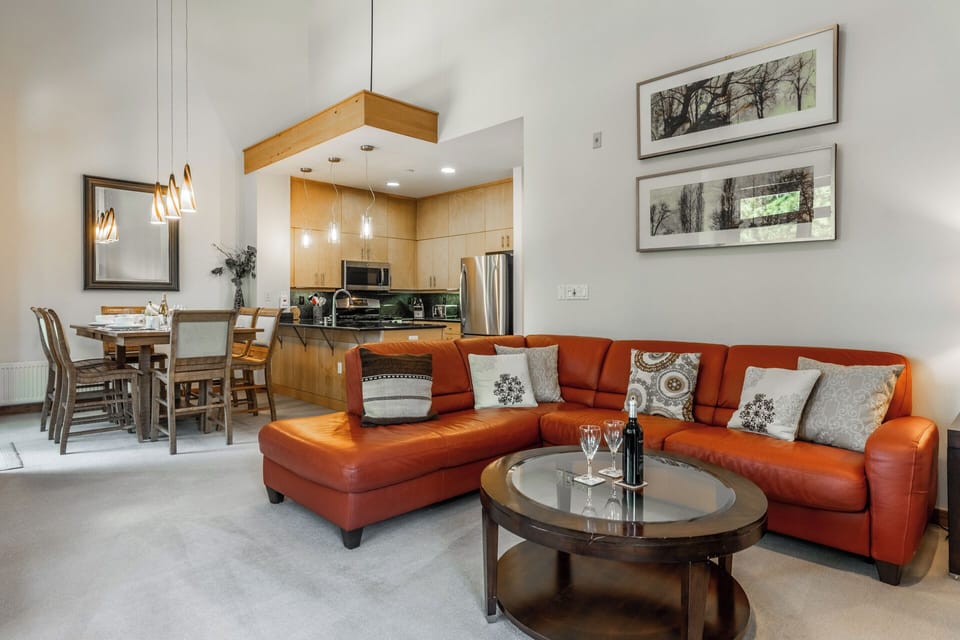Relax in your spacious open-plan living area, where a bold orange sofa and stylish round coffee table invite you to unwind after a day exploring the area.