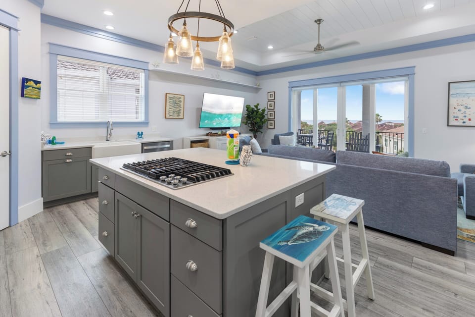 Step into your open-concept retreat where coastal charm meets modern comfort. The kitchen flows seamlessly into the living area, with a spacious island perfect for gathering, and doors opening to a private balcony with peaceful views.