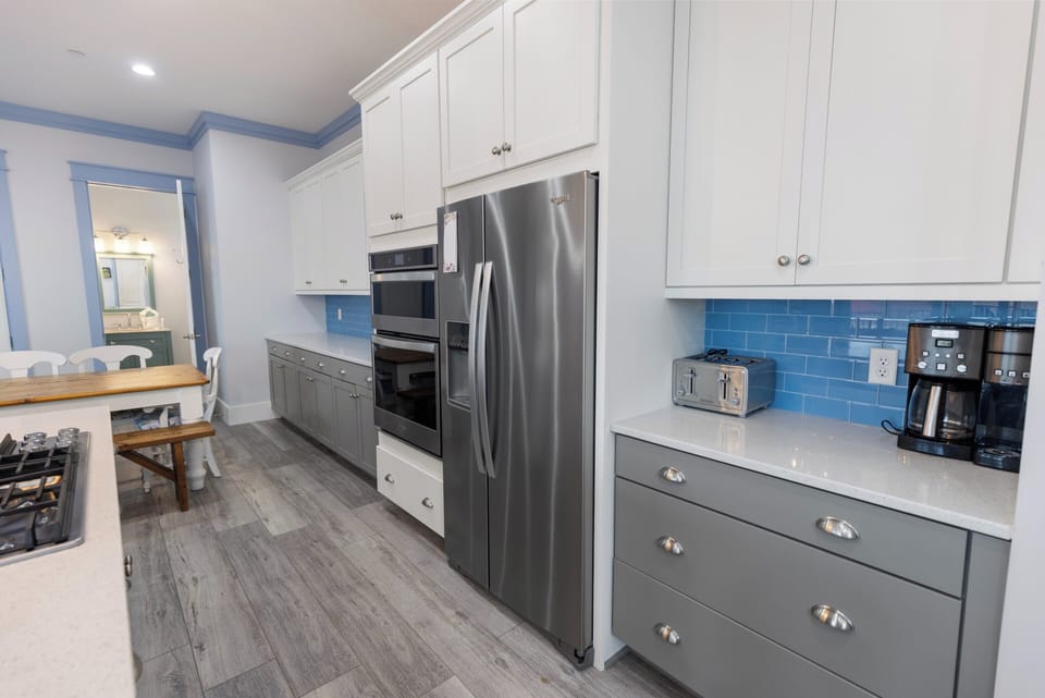 Your gourmet kitchen features stainless steel appliances, a spacious layout, and charming blue tile backsplash, perfect for preparing family meals together.