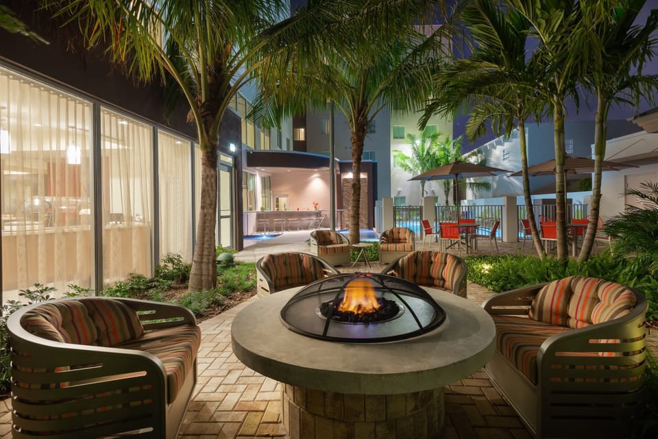 Gather around the cozy fire pit surrounded by palm trees for an evening of warmth and relaxation.