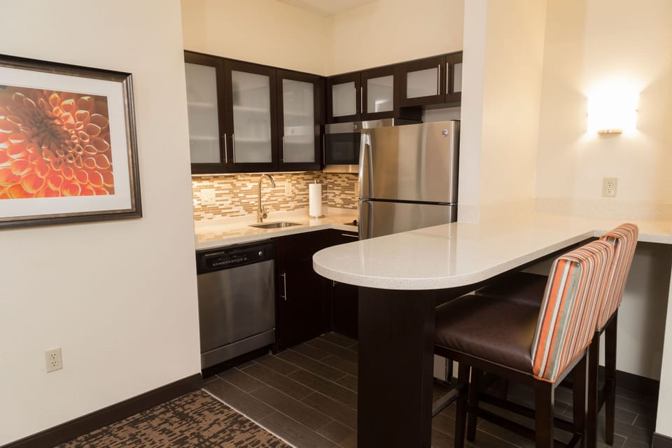 Fully equipped kitchen with stainless steel appliances and bar seating.