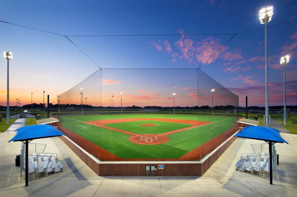 Nearby sports complex with illuminated baseball fields at sunset.