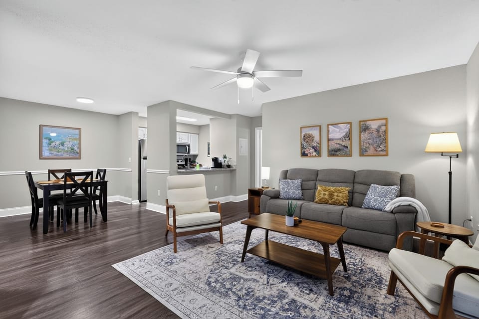 Stylish living room with sofa, two accent chairs, coffee table, area rug, warm decor, and open layout with easy access to dining area and kitchen.