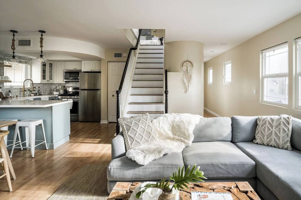 Living room with West Elm sofa, teak coffee table.  Stairs behind lead to 3rd floor bedroom loft with access to private rooftop patio.
