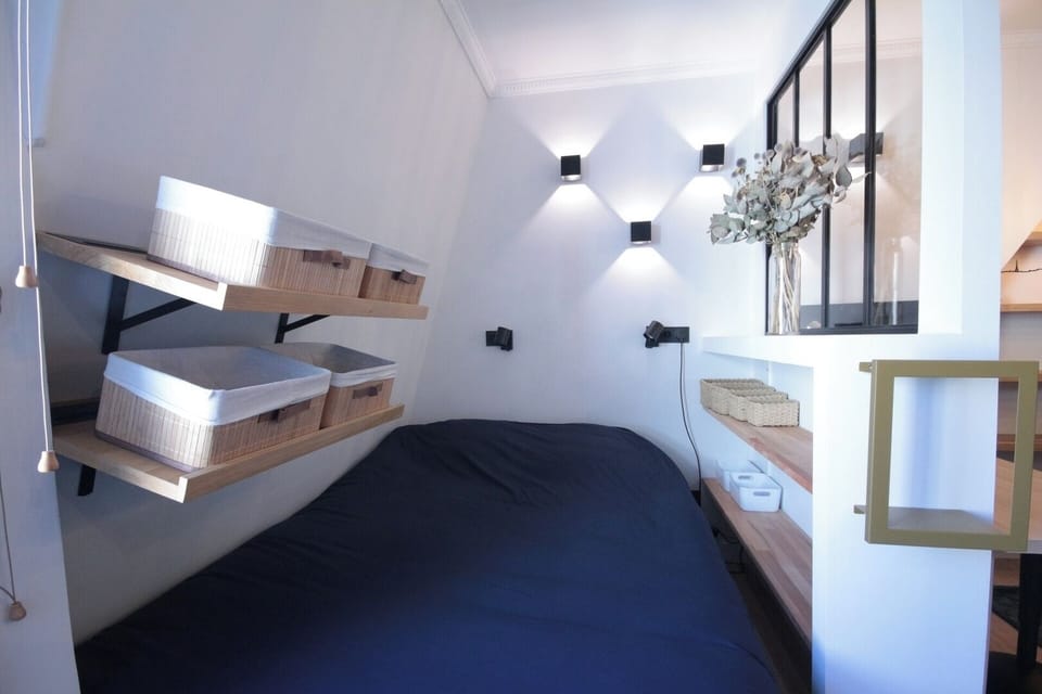 Espace nuit cosy séparé par verrière dans un studio rénové à Montmartre