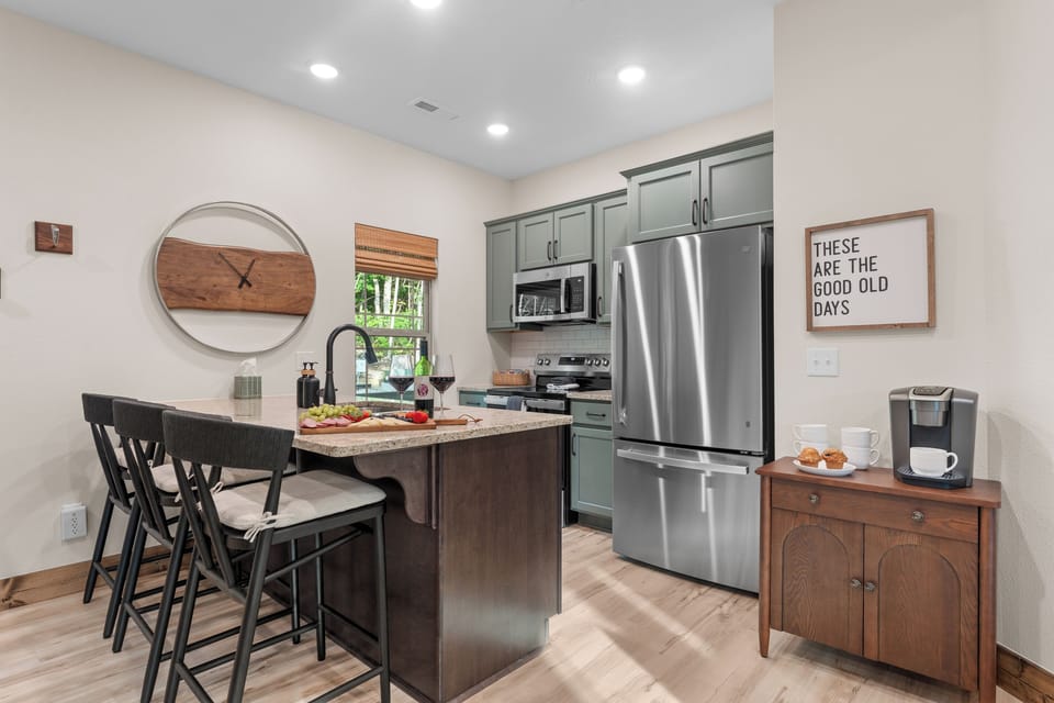 Cook breakfast in a full kitchen with beautiful sage cabinets, a stone island, and a coffee bar ready at sunrise.