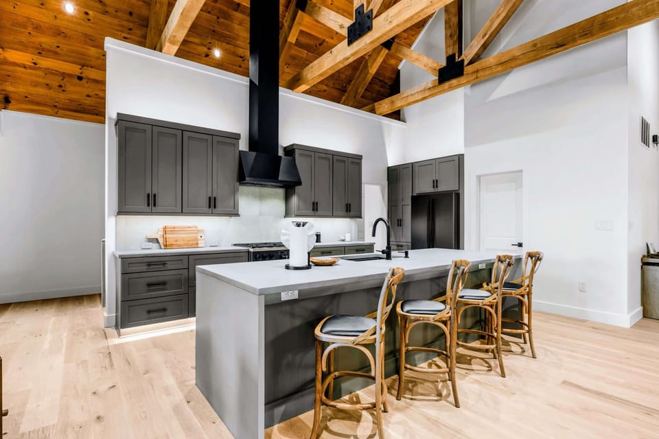 Kitchen - From the living side: perimeter range wall, big island, and wood doors to the backyard.