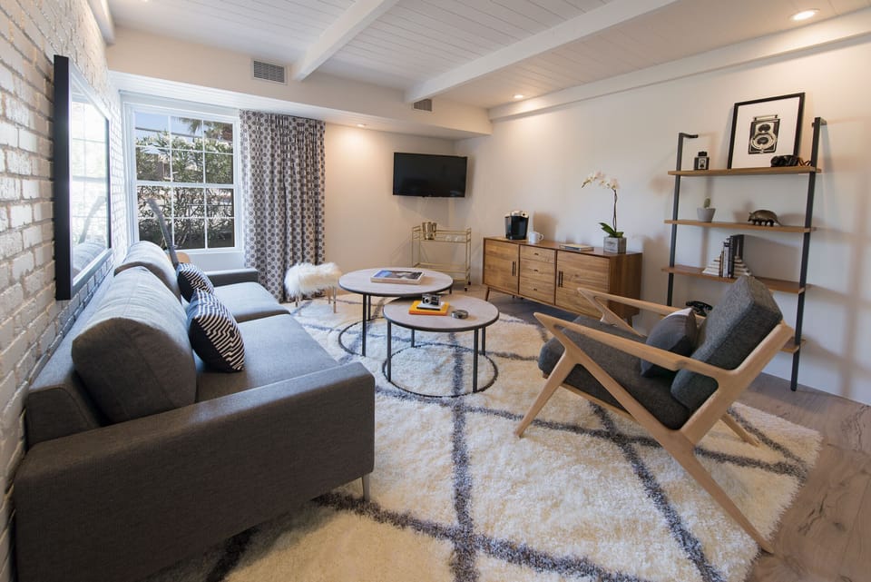 Open-concept living space with exposed ceiling beams and comfortable, chic seating arrangements.