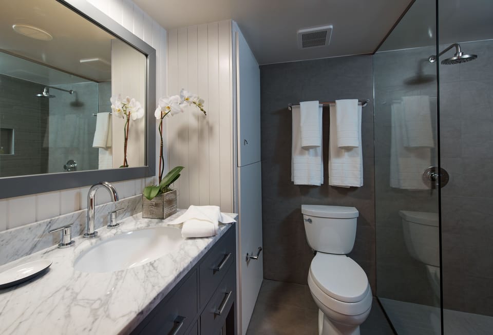 Sleek modern bathroom with a marble-top vanity and a pristine, contemporary glass shower.